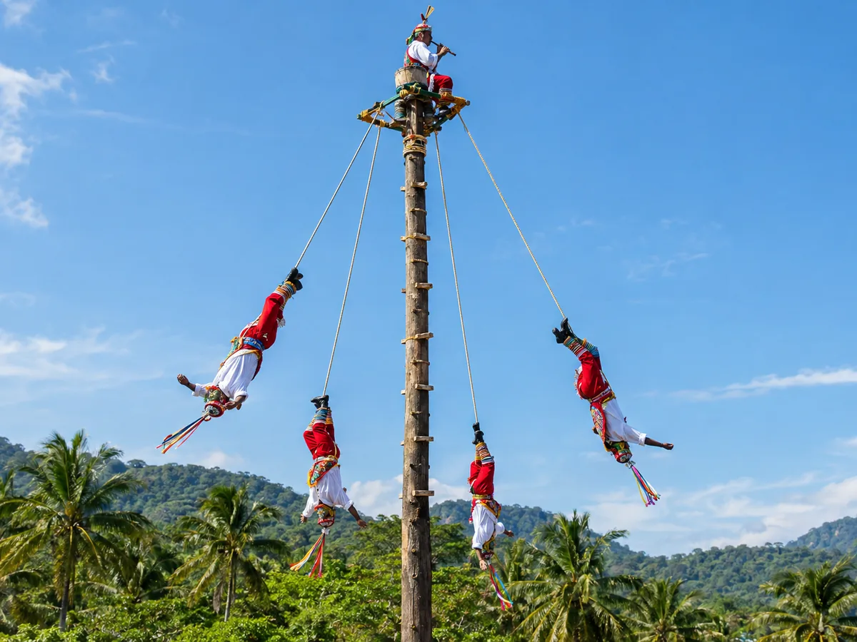 Voladores de Papantla, die an Seilen von einem hohen Holzpfahl herabsteigen